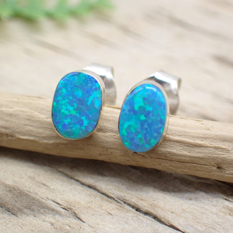 sterling silver blue opal oval stud earrings on a piece of driftwood