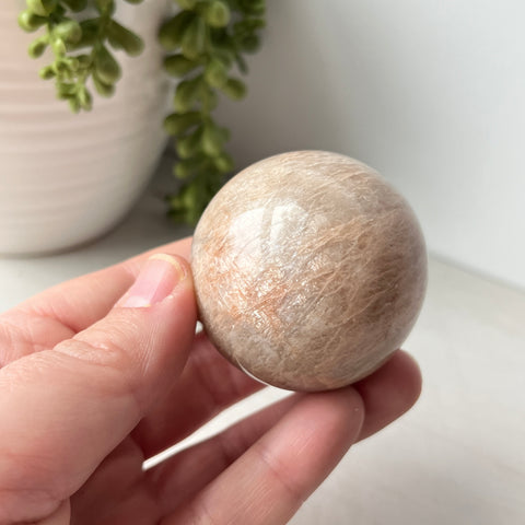 Esfera de piedra lunar de melocotón en un lindo soporte