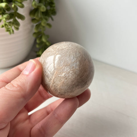 Esfera de piedra lunar de melocotón en un lindo soporte