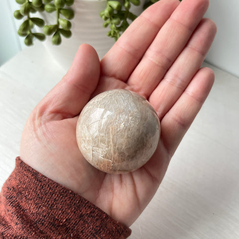 Esfera de piedra lunar de melocotón en un lindo soporte