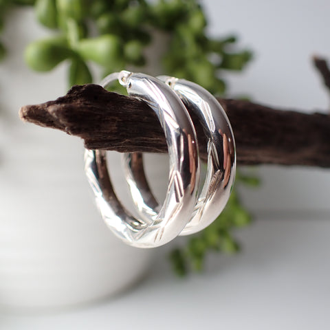 sterling silver open etched design hoop earrings hanging on driftwood