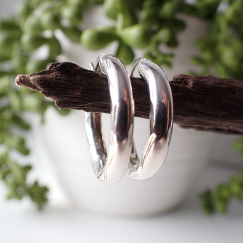 sterling silver open etched design hoop earrings hanging on driftwood