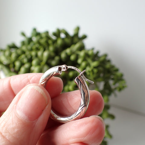 sterling silver open etched design hoop earrings hanging on driftwood